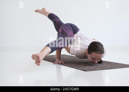 Flexible yogi practicing yoga by wall at studio stock photo