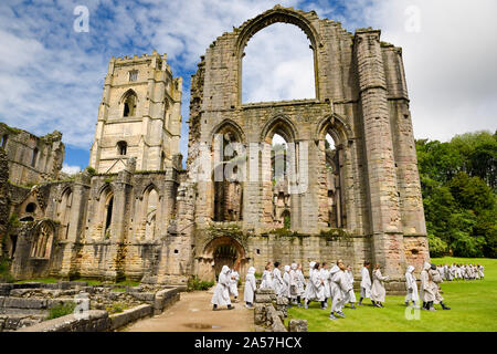 Fountains Abbey Cistercian monastery church with Tower and Chapel of Altars and group of students in monk robes North Yorkshire England Stock Photo