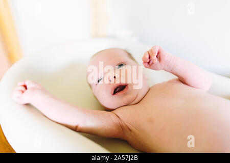 A newborn baby boy stretches while laying on a changing table Stock Photo