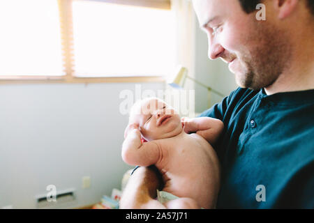 A new dad holds his newborn baby boy while he stretches Stock Photo