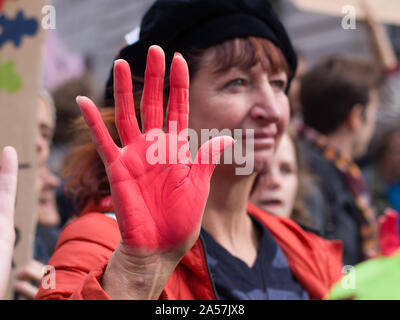 Whitehall, London, UK. 18 October 2019. Environmental campaigners Extinction Rebellion, including Red Rebellion, families and young children protest along Whitehall to reach outside the gates of Downing Street. Activists sing and hold their hands which are painted red to symbolise blood. Protesters demand decisive action from the UK Government on the global environmental crisis.