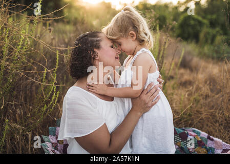 Tender moment between mother & child touching faces with eyes closed Stock Photo