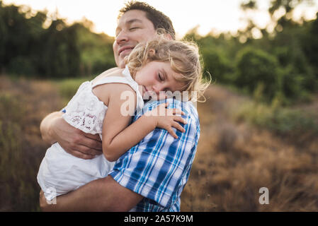 Smiling dad cuddles child sleeping on his shoulder Stock Photo