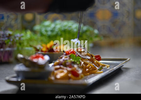 Food concept. The chef is decorated with fresh herbs and flowers dishes in the restaurant. The process of making spaghetti with seafood. Stock Photo