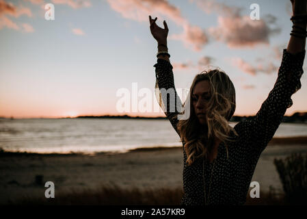 woman doing yoga at sunset at the beach Stock Photo