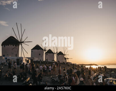 Mykonos, Greece - September 23, 2019: People watching sunset near windmills in Hora (Mykonos Town), capital of the island and one of the best examples Stock Photo