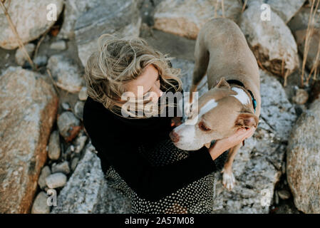 woman and dog sitting on rocks Stock Photo