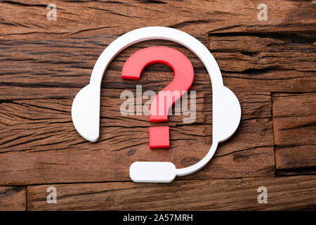 Customer Support Concept Headphones And Question Mark On Wooden Desk Stock Photo