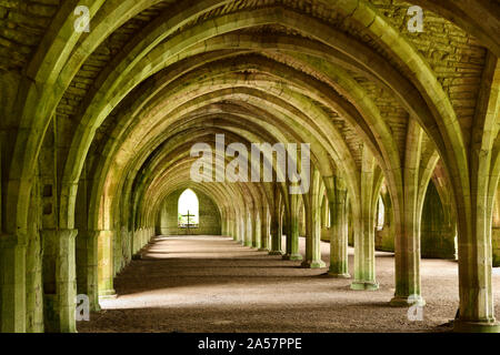 Fountains Abbey Cistercian monastery ruins vaulted stone arch ceiling of the monks cellarium with cross at window North Yorkshire England Stock Photo