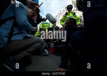 A climate protest group member (Extinction Rebellion) getting interviewed by the media at the protests in Trafalgar Square in London, police surround. Stock Photo