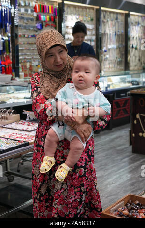 Woman with headscarf has small child on arm Stock Photo