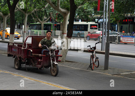 Man riding a tricycle moped with cargo space over the road Stock Photo