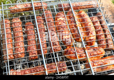 Delicious sausages from meat on a metal grid grilling over hot coals for a picnic lunch Stock Photo