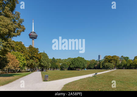 Outdoor sunny view of Innerer Grüngürtel, park in city center, with background of Colonius Broadcasting Tower against blue sky in Cologne, Germany. Stock Photo