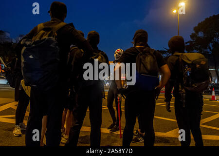 Gangs of Hong Kong protestors in sinister masks wield clubs and baseball bats on the streets of Hong Kong, goading the police Stock Photo