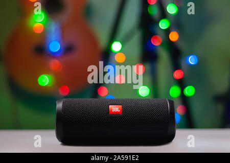BL Flip 4 Bluetooth Speaker close up shot in a cozy room with blurred Christmas lights and guitar on the background. Stock Photo
