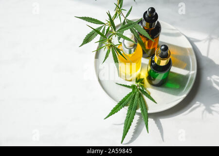 Glass bottle and dropper CBD OIL, THC tincture and cannabis leaf on background. Laboratory Production of cosmetics with CBD oil. Stock Photo