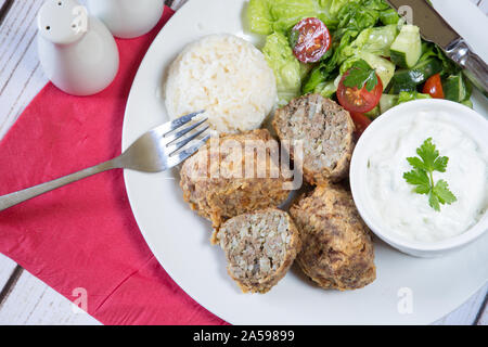 Traditional Turkish dish of Kadinbudu kofte, Cacik and Pilaf rice with Orzo served with fresh mixed salad Stock Photo