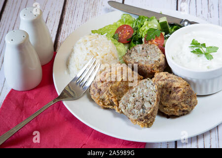 Traditional Turkish dish of Kadinbudu kofte, Cacik and Pilaf rice with Orzo served with fresh mixed salad Stock Photo