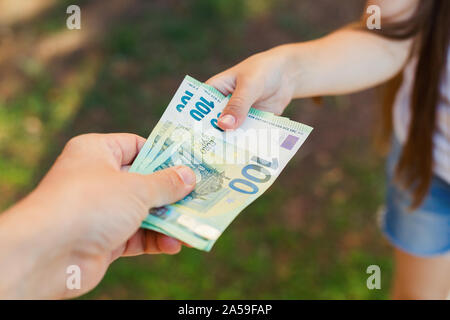 Male hand gives money to a child closeup, hundredth euro banknotes Stock Photo
