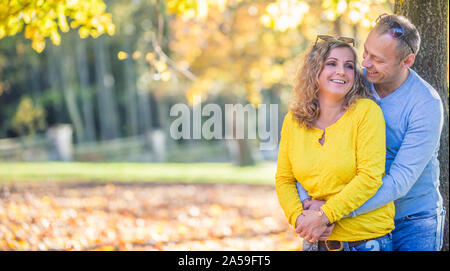 Happy mature couple in autumn park in the embrace. Stock Photo