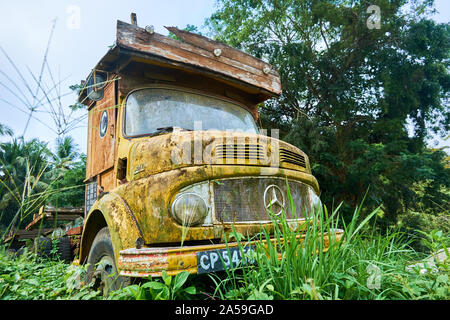 An old, yellow, rusting and moss covered 1960's era Mercedes Benz truck cab. In Kuala Lipis, Pahang, Malaysia. Stock Photo