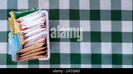sugar packets on a Checkered white and green table cloth Stock Photo