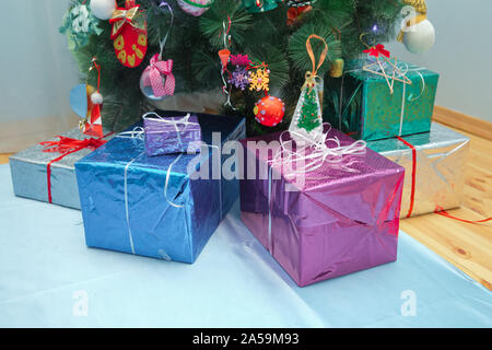 gifts under the Christmas tree . Christmas gifts packed with colorfull paper and tapes under decorated tree . Christmas tree and many gifts . Stock Photo