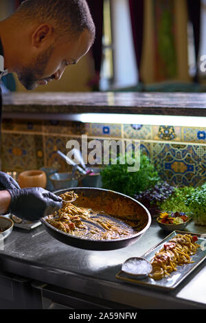 Food concept. The chef mixes spaghetti in a pan the tomatoes and oysters, dish in a restaurant. The process of cooking spaghetti with seafood. Stock Photo