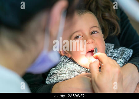 Pediatric dentist examining a little boys teeth in the dentists chair at the dental clinic. Dentist examining little boy's teeth in clinic. Stock Photo