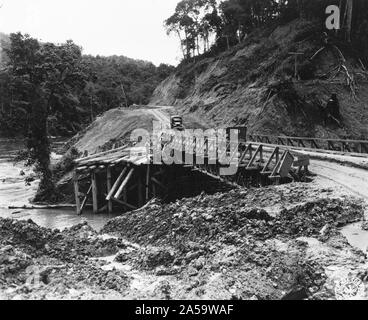 Original caption: View of newly constructed bridge with modern structure and whats left of old bridge made from logs. The old bridge was constructed by Chinese Engineers with very primitive equipment and due to the heavy rain falls and weight it was carrying gave-way during the early part of the monsoon. Mile 52 along the Ledo Road June 1944. Stock Photo