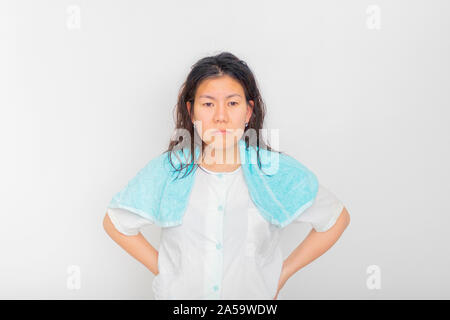 The Asian woman in blue pajamas is standing in studio with one small blue towel over her shoulder. Stock Photo
