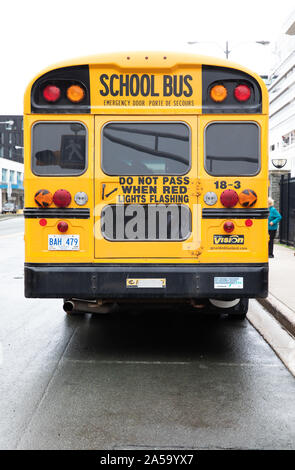 Yellow school bus parked alongside the cruise ship Arcadia in St John's Newfoundland, Canada Stock Photo