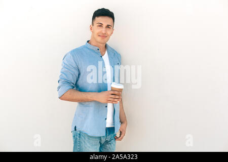 Outdoors Leisure. Stylish guy standing isolated on white with cup of coffee smiling playful to camera Stock Photo