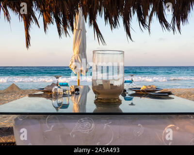 Gazebo on the beach with table set. Candle on table. Relaxing context. Nobody on the beach. Blue sea on the back. Fabulous holiday Stock Photo