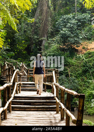 Young fashionable woman on a bamboo bridge Stock Photo