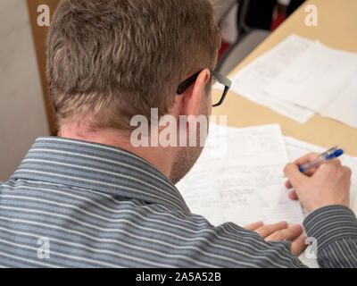 A man writing up paperwork at work. Stock Photo