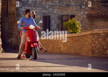 Just married happy man and woman riding motor scooter in city . Stock Photo