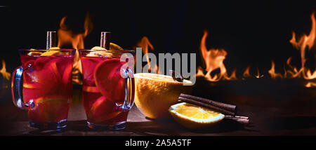 Two cups of christmas mulled wine against a fire. Gluhwein or hot wine. Traditional winter drink. Panorama. Banner Stock Photo