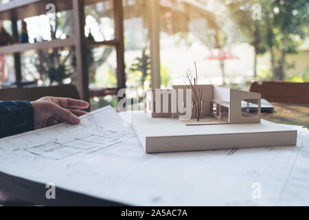 An architect working on an architecture model with shop drawing paper on table Stock Photo