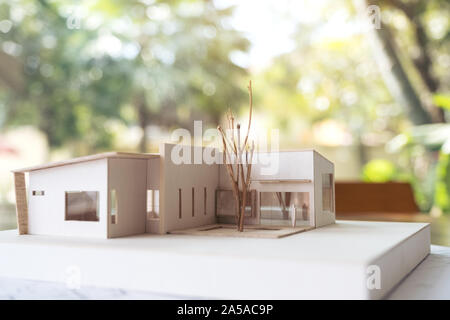 An architecture model with shop drawing paper and laptop on table in office with blur nature background Stock Photo