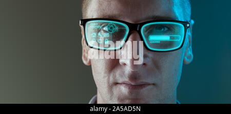 A close up image of a man wearing smart arugmented reality glasses with virtual screen displaying icons and loading screen - modern technology concept Stock Photo