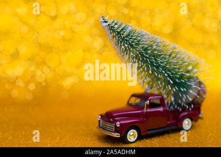 Toy car carries Christmas tree for holiday. Stock Photo
