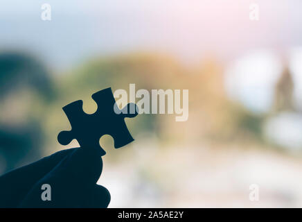 Closeup image of a hand holding a jigsaw puzzle with blur background Stock Photo