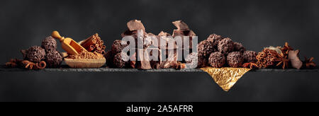 Chocolate truffles with broken pieces of chocolate. Chocolate with ingredients and spices on a dark background. Copy space. Stock Photo