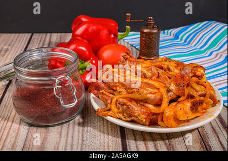 Lamb ribs marinated with spices in a plate on the table. With tomatoes, sweet peppers and a jar of spices Stock Photo