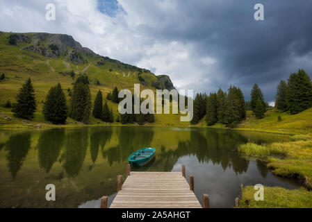 tied rowing boat on Lac Retaud mountain lake with clear water reflections Stock Photo