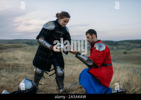 Medieval knight helps his friend to put on armor Stock Photo