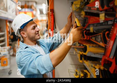 Male customer choosing saw in hardware store Stock Photo