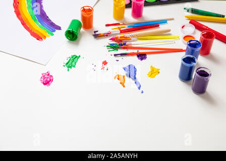 Creative kids, rainbow drawing. Colorful finger paints set and paint brushes on white color background, copy space Stock Photo